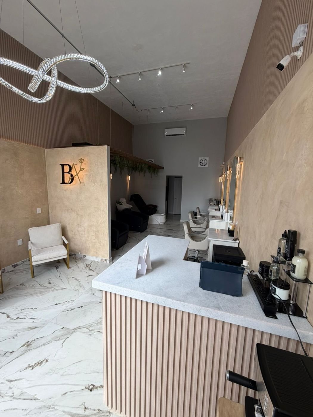 Recepción de Bloom Atelier con el logotipo BA iluminado y las estaciones al fondo